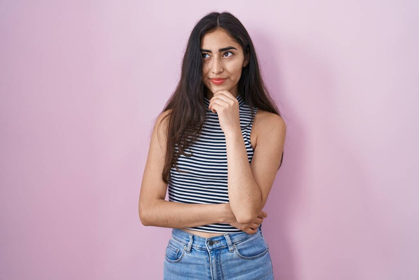 Young teenager girl wearing casual striped t shirt with hand on chin thinking about question, pensive expression. smiling with thoughtful face. doubt concept.  - Photo, Image