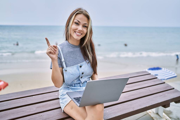 Young caucasian woman working using computer laptop outdoors smiling happy pointing with hand and finger to the side  - Photo, image