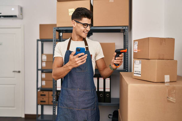 Young hispanic man ecommerce business worker scanning package at office - 写真・画像
