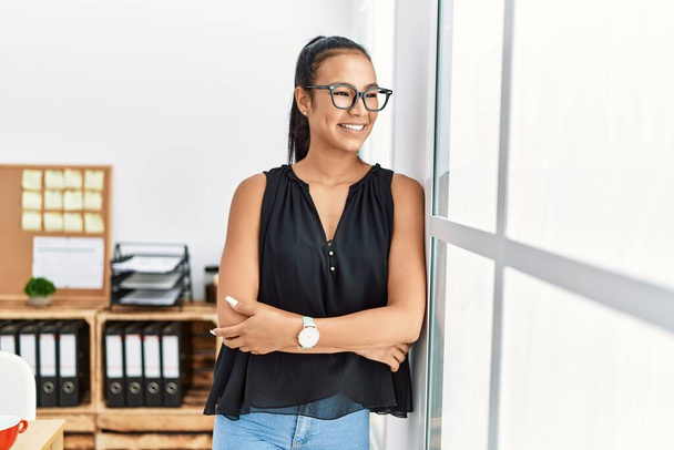 Young latin woman smiling confident standing with arms crossed gesture at office - Photo, Image