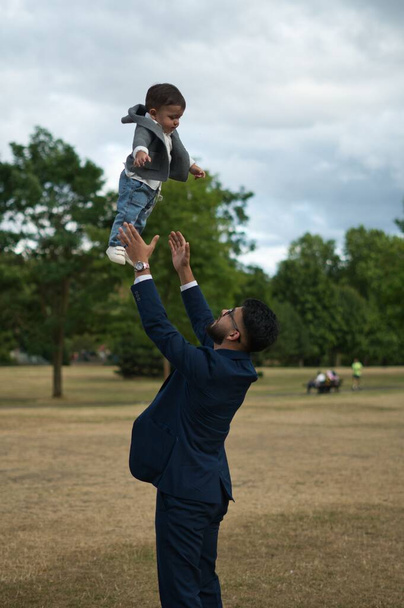 Asyalı Pakistanlı Baba 11 aylık bebeğini Londra Luton İngiltere 'deki yerel parkında tutuyor. - Fotoğraf, Görsel