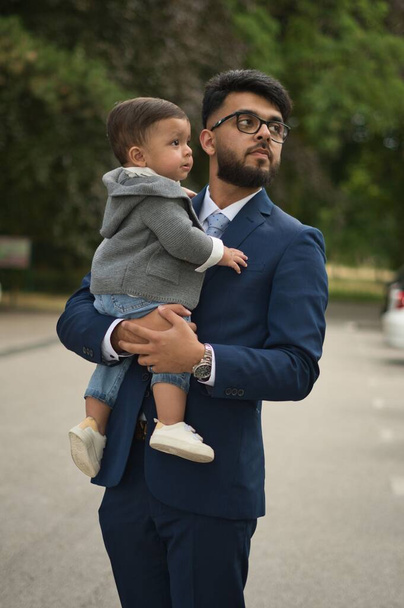 Asyalı Pakistanlı Baba 11 aylık bebeğini Londra Luton İngiltere 'deki yerel parkında tutuyor. - Fotoğraf, Görsel