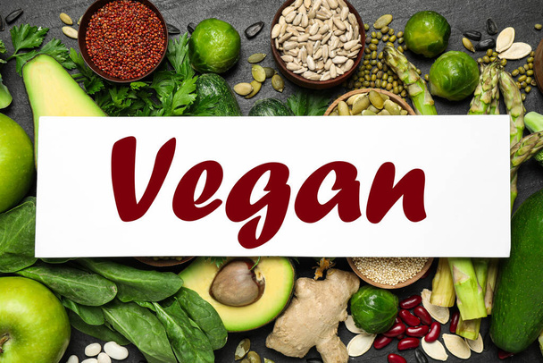 Paper card with word Vegan and fresh vegetables on grey background, flat lay - Фото, зображення