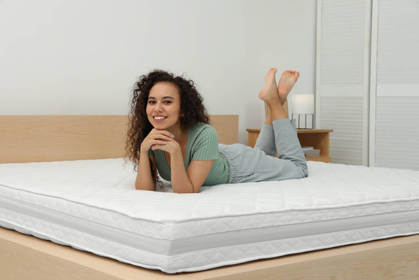 Happy young African American woman on bed with comfortable mattress at home - Valokuva, kuva