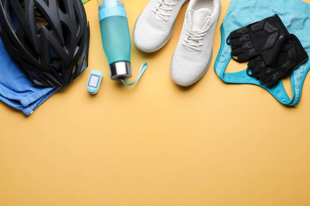 Flat lay composition with different cycling accessories and clothes on pale orange background, space for text - Φωτογραφία, εικόνα