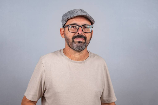 Kypsän liikemiehen muotokuva silmälasit harmaalla taustalla. Happy 60s vanhempi brasilialainen mies katselee kameran eristetty yli harmaa seinä kopiotilaa - Valokuva, kuva