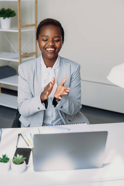 Усміхнена афро-американська жінка розмовляє на відеовиклику, використовуючи ноутбук, що показує жести на екрані. Дистанційне навчання
. - Фото, зображення