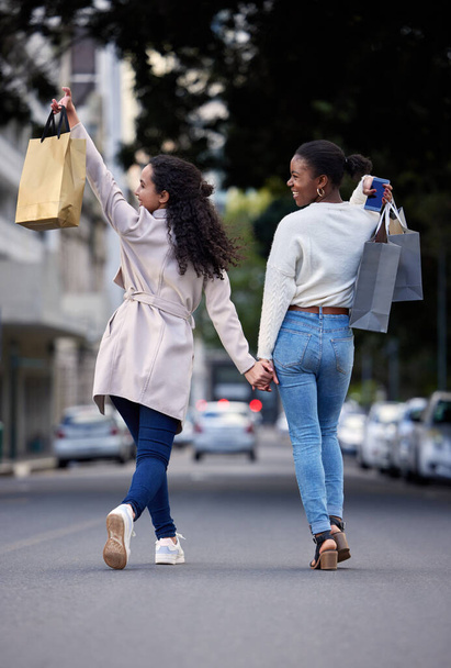 Making our way downtown. two friends cheerfully walking down the street after spending the day shopping - Фото, изображение
