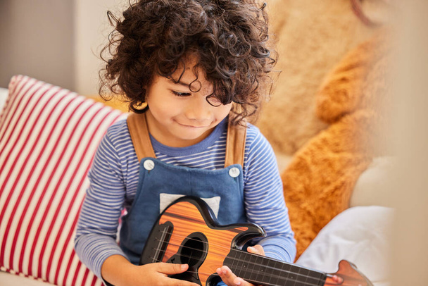 Слухайте мене, грайте. маленький хлопчик грає на гітарі, сидячи вдома
 - Фото, зображення