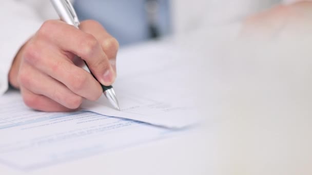 Closeup of the hands of a healthcare professional drafting a medical letter or form. A GP filing a document in an office. Doctor writing a prescription on paper on his desk at the hospital - Video