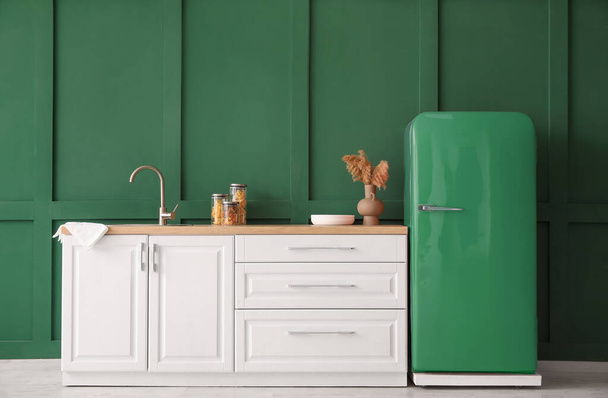 Kitchen counter with sink and retro fridge near green wall - Photo, image