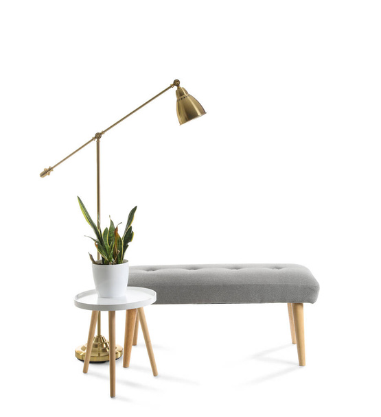 Table with houseplant, soft bench and lamp on white background - Photo, Image