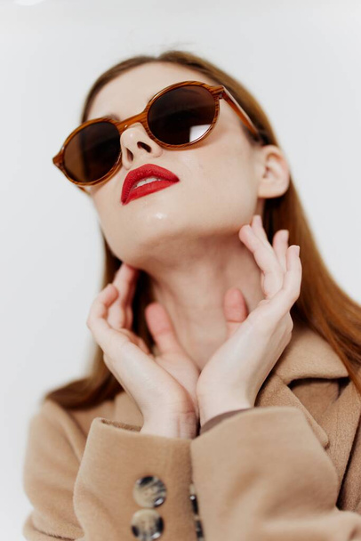 Una joven elegante en gafas y un abrigo posa para un catálogo de ropa sobre un fondo blanco. Concept Fashion. Foto de alta calidad - Foto, imagen