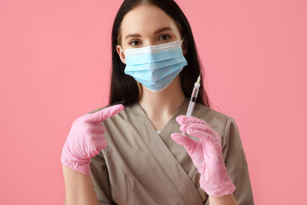 Doctor with syringe on pink background - Zdjęcie, obraz