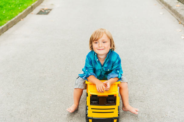 Menino pequeno brincando com o carro de brinquedo grande, ao ar livre
 - Foto, Imagem