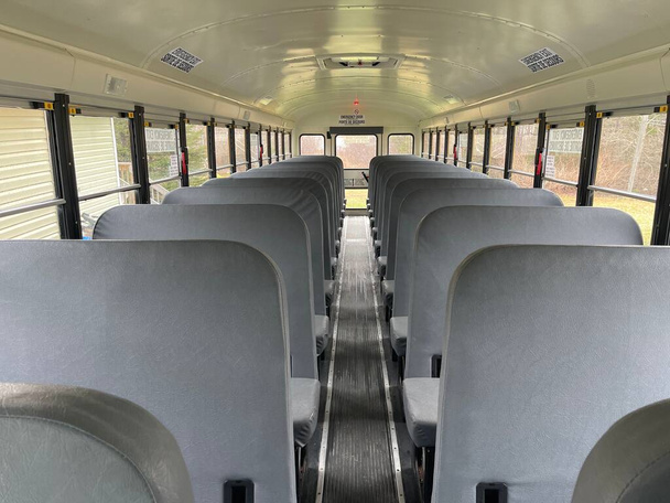A shot of School Bus interior seatings showing a view down the aisle to the back door - 写真・画像