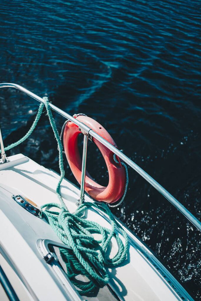 A vertical shot of a lifesaving ring and rope on the side of a boat - Фото, изображение
