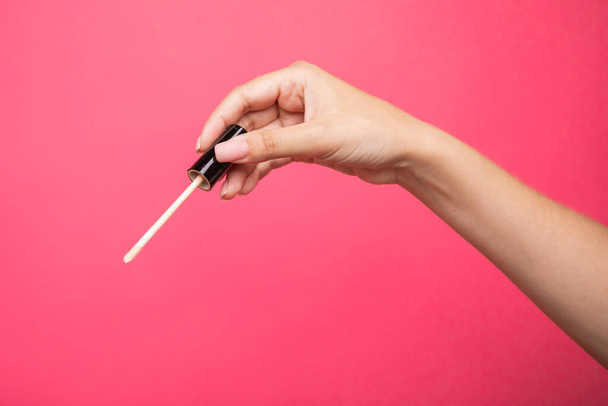 Woman hands holding concealer applicator isolated on pink background. High quality photo - Fotografie, Obrázek