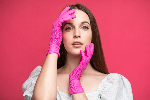 Beauty Face Skin Care. Beautiful Woman Face with hands in gloves near face. High quality photo - Fotografie, Obrázek