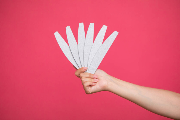Set of nail files in woman hand on pink background. Manicurist equipment. High quality photo - 写真・画像