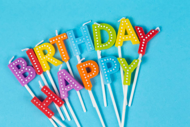 Кольорові свічки в листах з написом "З днем народження" ізольовані на синьому фоні. - Фото, зображення