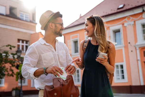 Happy young couple of travelers with map having fun on vacation together. People happiness concept - Photo, Image