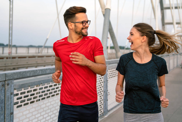 Early morning workout. Happy couple running across the bridge. Sport living healthy lifestyle. - Foto, Imagem