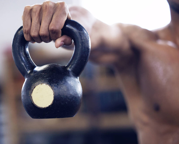 Heavy weights and hard work get big results. an unrecognisable man working out with a kettle bell at the gym - Foto, imagen