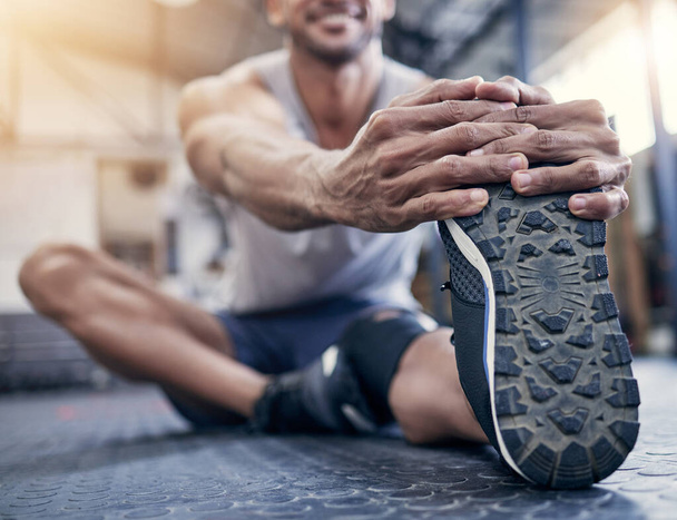 Getting ready to power up. Closeup shot of an unrecognisable man stretching his legs while exercising in a gym - Photo, image