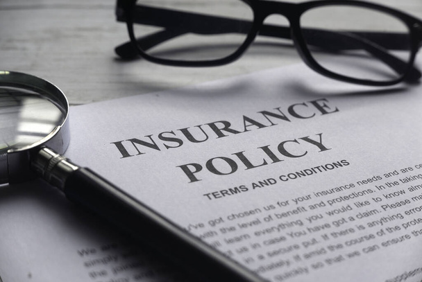Selective focus of magnifying glass,glasses and Insurance Policy letter on a white wooden background. - Foto, Imagen