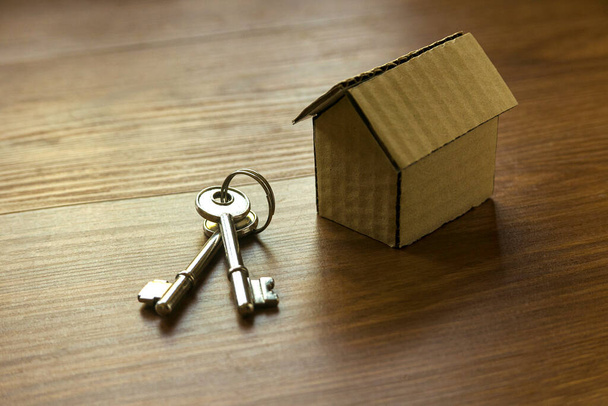 Close up of house model and keys on wooden background. - Fotó, kép