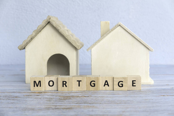 Concept of property, real estate and mortgage with a house model and wooden cube of a MORTGAGE word. - 写真・画像