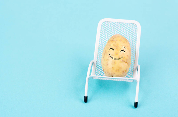Potato with a funny face is sitting in lounge chairs, happy holiday, greeting card  - 写真・画像