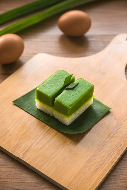 Selektiver Schwerpunkt von Kuih Seri Muka, einem traditionellen malaysischen zweischichtigen Dessert mit gedämpftem klebrigem Reis, der die untere Hälfte bildet, und einer grünen Puddingschicht aus Pandanasaft. - Foto, Bild
