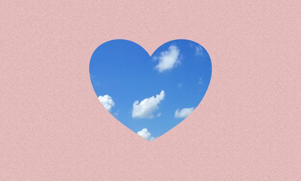 A love or heart icon fill with blue sky and clouds on pink paper background. - Foto, imagen