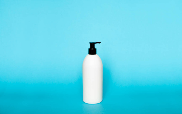 White plastic soap dispenser pump bottle isolated on blue background. Skin care lotion. Bathing essential product. Shampoo bottle. Bath and body lotion. Fine liquid hand wash. Bathroom accessories - Fotó, kép