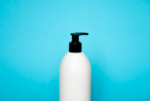 White plastic soap dispenser pump bottle isolated on blue background. Skin care lotion. Bathing essential product. Shampoo bottle. Bath and body lotion. Fine liquid hand wash. Bathroom accessories - Foto, afbeelding
