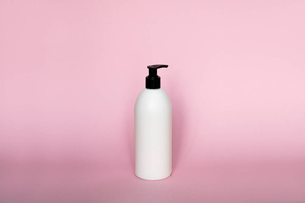 White plastic soap dispenser pump bottle isolated on pink background. Skin care lotion. Bathing essential product. Shampoo bottle. Bath and body lotion. Fine liquid hand wash. Bathroom accessories - Photo, Image
