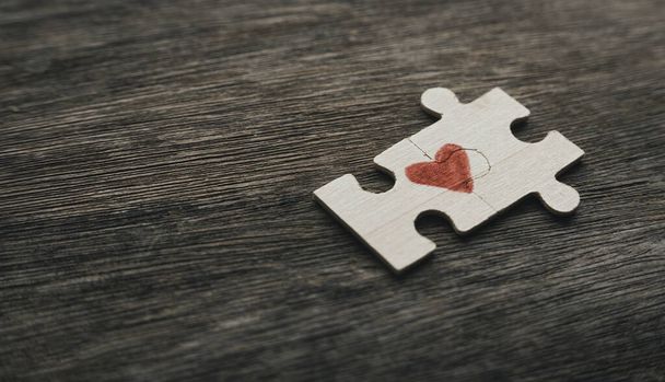 Selective focus of two pieces of a puzzle forming a heart on a wooden rustic background with copy space. Love concept. - Foto, Imagem