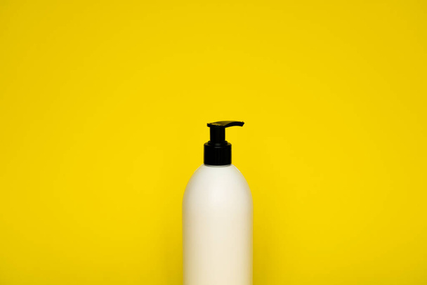 White plastic soap dispenser pump bottle isolated on yellow background. Skin care lotion. Bathing essential product. Shampoo bottle. Bath and body lotion. Fine liquid hand wash. Bathroom accessories - Foto, Imagem
