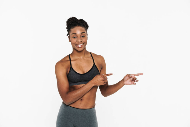 Young black sportswoman smiling and pointing finger aside isolated over white background - Φωτογραφία, εικόνα