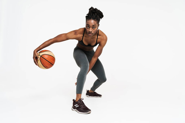 Young black sportswoman working out with basketball isolated over white background - Foto, immagini