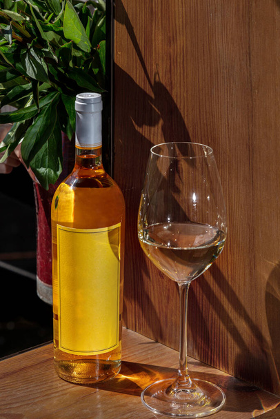 Бутылка вина и стекло на деревянном фоне с букетом цветов - Фото, изображение