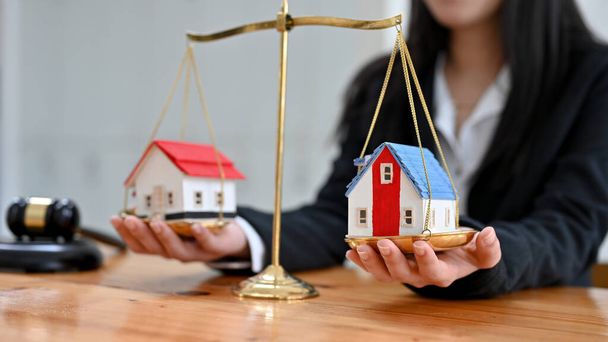 Female lawyer protecting a house model on a scales of justice. Property and legal concept. Houses Litigation. cropped image - Fotoğraf, Görsel