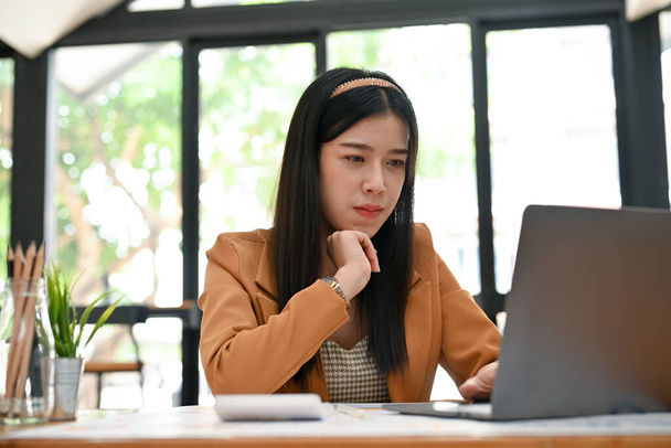 Professional millennial Asian female financial consultant concentrated working on her business task on the laptop computer. - Foto, immagini