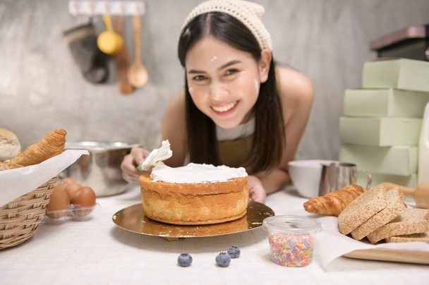 A Young beautiful woman is baking in her kitchen , bakery and coffee shop business - Foto, Imagem