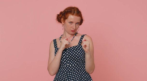 Greedy avaricious redhead young woman showing fig negative gesture, you dont get it anyway. Rapacious, avaricious, acquisitive. Body language. Refusal fig sign. Ginger girl indoor on pink background - Zdjęcie, obraz
