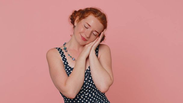 Tired young redhead woman in dress yawning, sleepy inattentive feeling somnolent lazy bored gaping suffering from lack of sleep. Ginger girl with freckles isolated alone on pink studio background - Foto, afbeelding