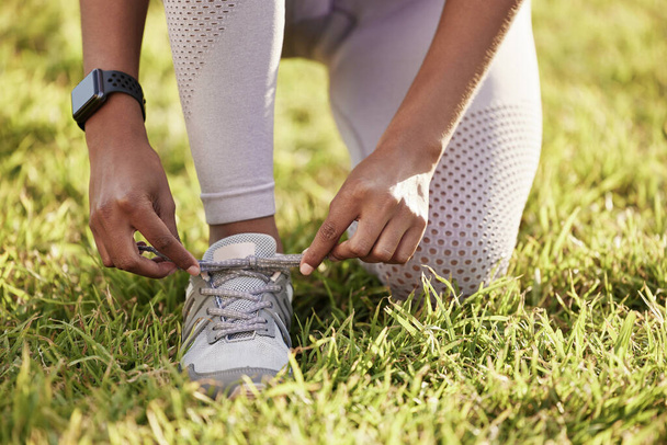 Dont allow yourself to stumble. Closeup shot of an unrecognisable woman tying her shoelaces while exercising outdoors - Photo, Image