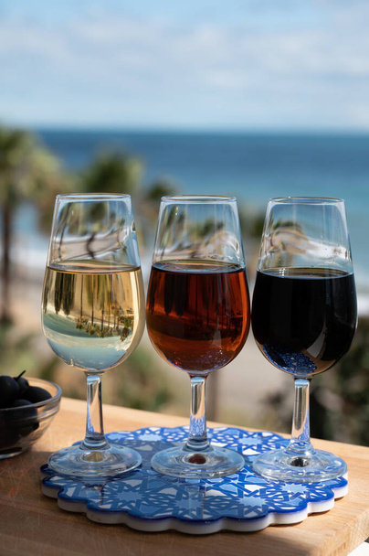 Γευστική δοκιμή ισπανικού γλυκού και ξηρού οχυρωμένου οίνου Vino de Jerez sherry και πράσινων ελιών με θέα στη γαλάζια θάλασσα και την παραλία κοντά στο El Puerto de Santa Maria, Ανδαλουσία, Ισπανία - Φωτογραφία, εικόνα